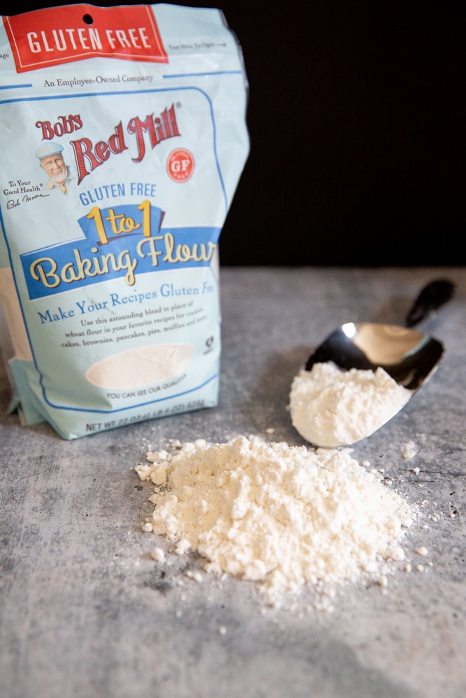 A bag of gluten free flour with a pile of flour in the foreground.
