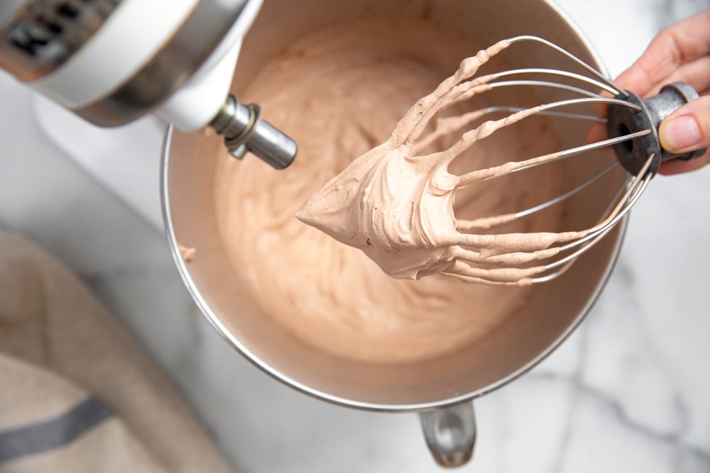 Process shot showing how to make the chocolate whipped cream in a stand mixer.