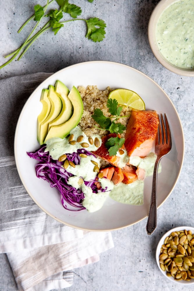 Grain bowl with salmon, cabbage and avocado, drizzled with cilantro yogurt sauce. 