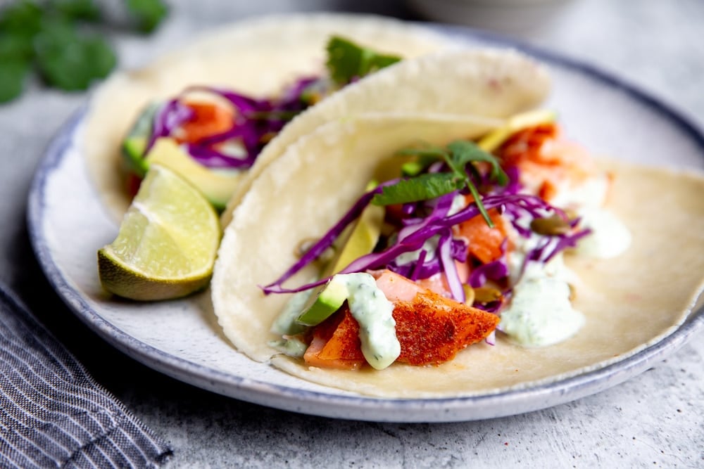 Slow cooker salmon in tacos with shaved cabbage, avocado slices and yogurt cilantro sauce. 