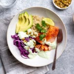 Slow cooker salmon with cabbage and avocado over quinoa in a serving bowl, drizzled with yogurt sauce.