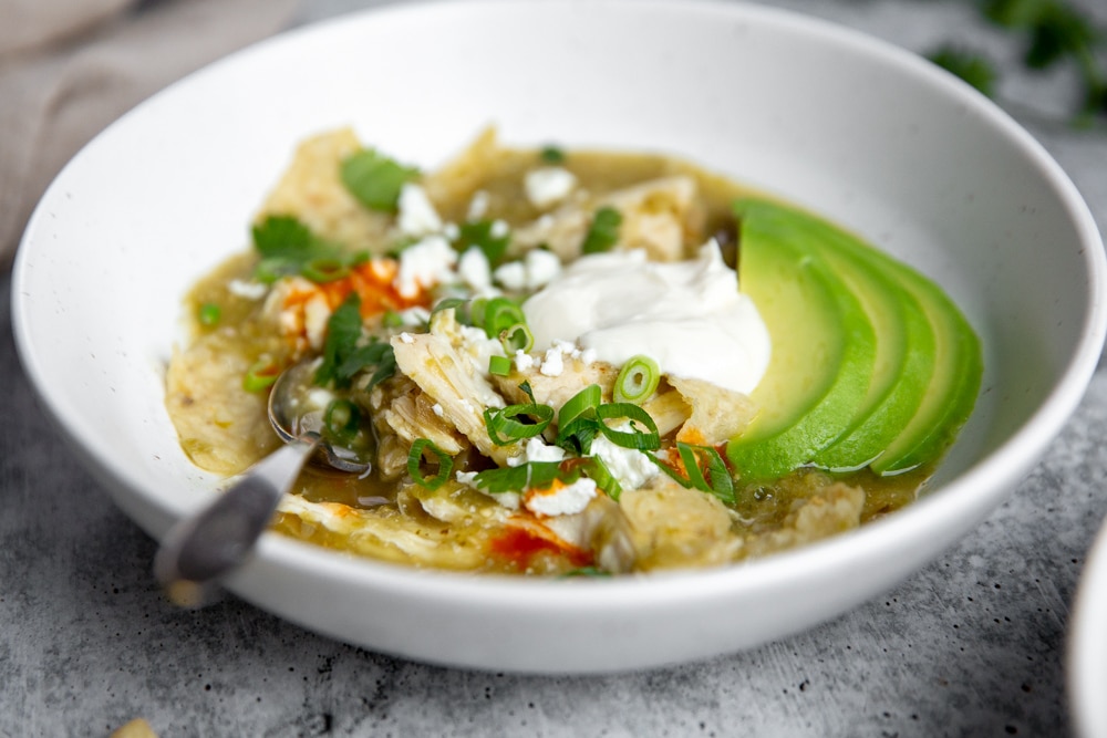 Close up of a bowl of chilaquiles stew with a spoon. 