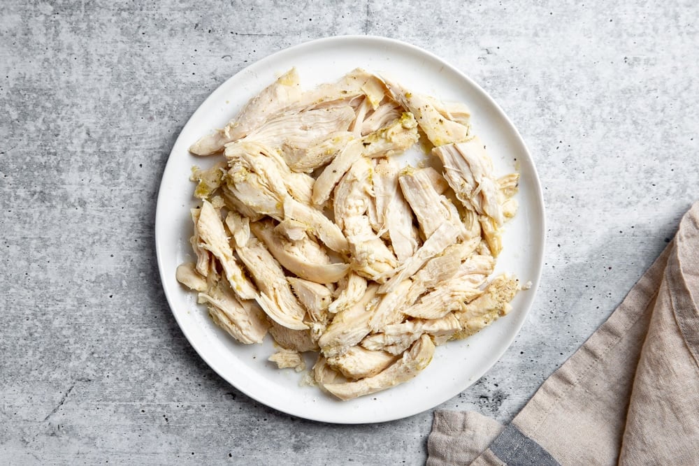 Process shot showing the shredded chicken on a plate. 