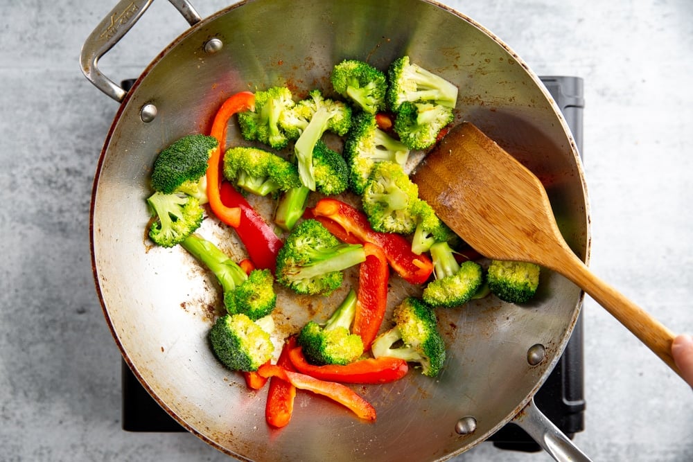 Process shot showing hardy vegetables cooking in a wok for the healthy stir fry recipe.