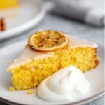 A slice of lemon olive oil cake on a plate with a dollop of whipped cream.
