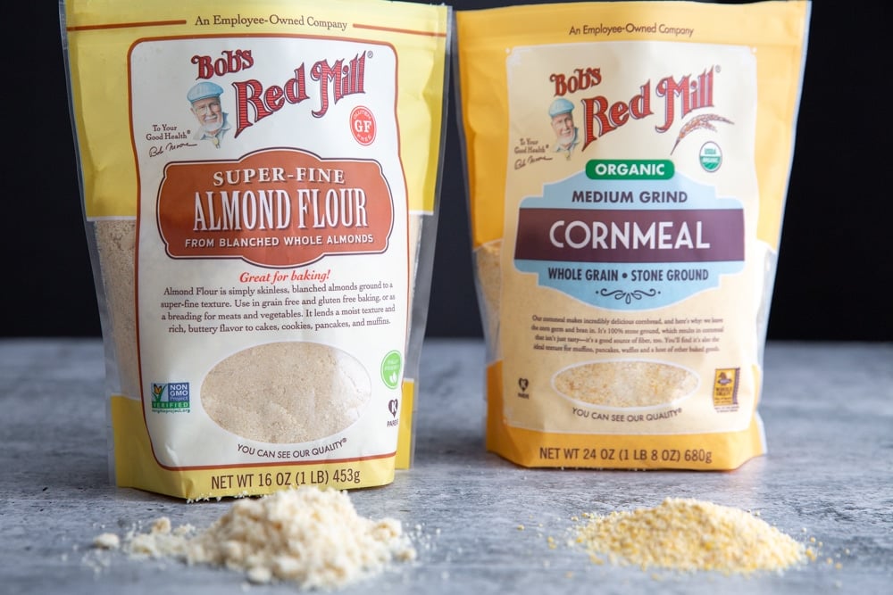 A bag of Bob's Red Mill Super-Fine Almond Flour and a bag of Bob's Red Mill Medium Grind Cornmeal on a counter.