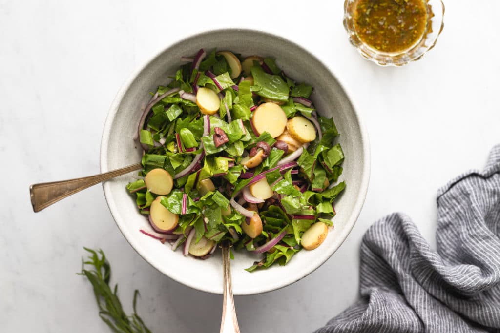 A bowl of fingerling potato and dandelion greens salad.