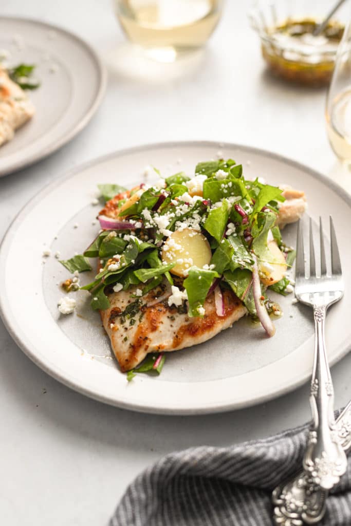 Chicken paillard on a plate topped with dandelion greens salad. 