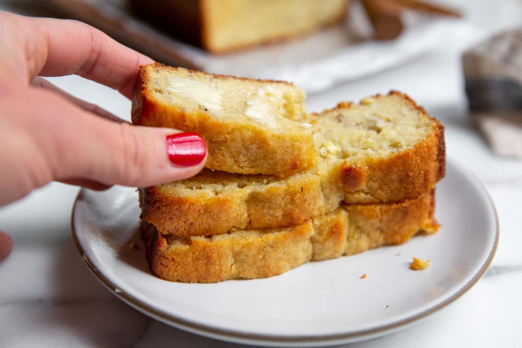 A hand grabbing a piece of banana bread from a stack.