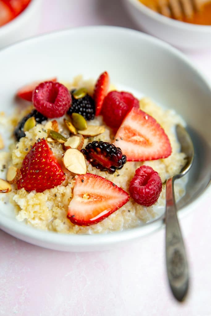 Close up of millet breakfast porridge in a bowl, topped with fresh berries. 