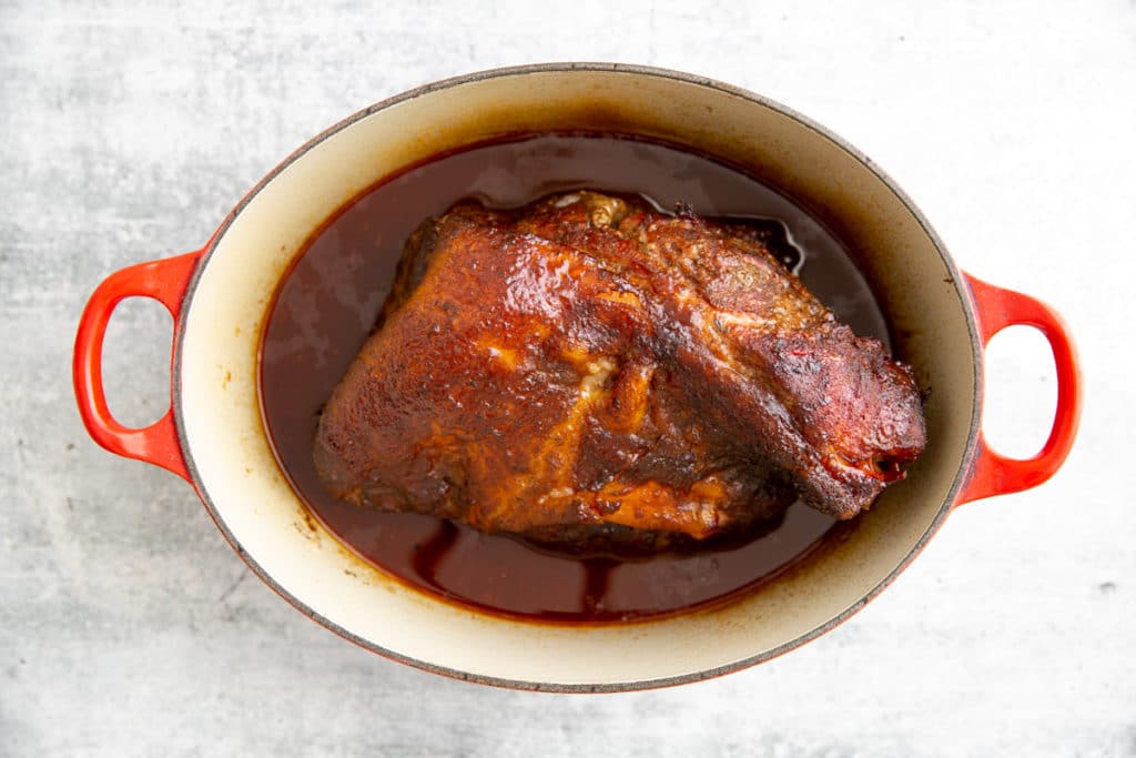Smoked pork shoulder in Dutch oven with barbecue sauce. 