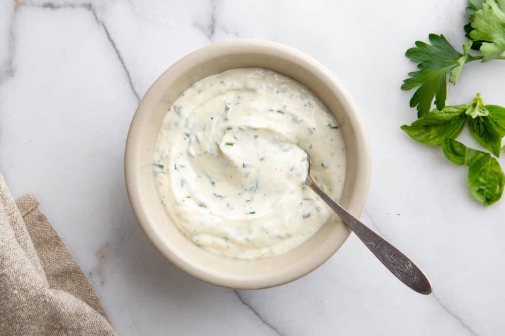 Herbed aioli in a bowl with a spoon. 