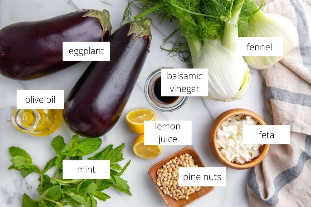 The ingredients for the eggplant salad arranged on a marble surface.
