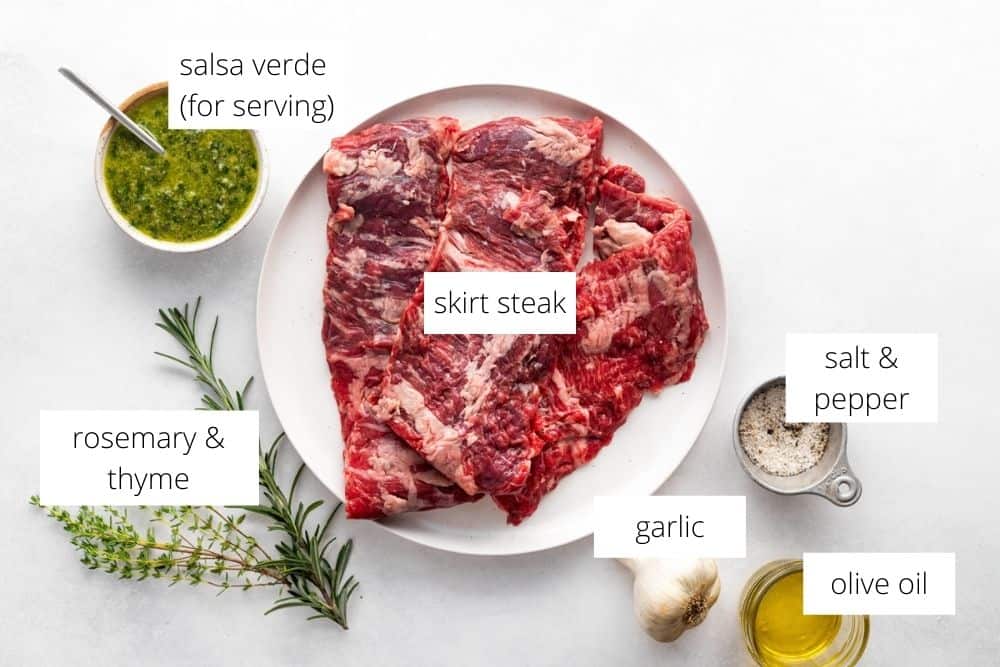 All of the ingredients for the grilled skirt steak recipe arranged on a white surface with labels.