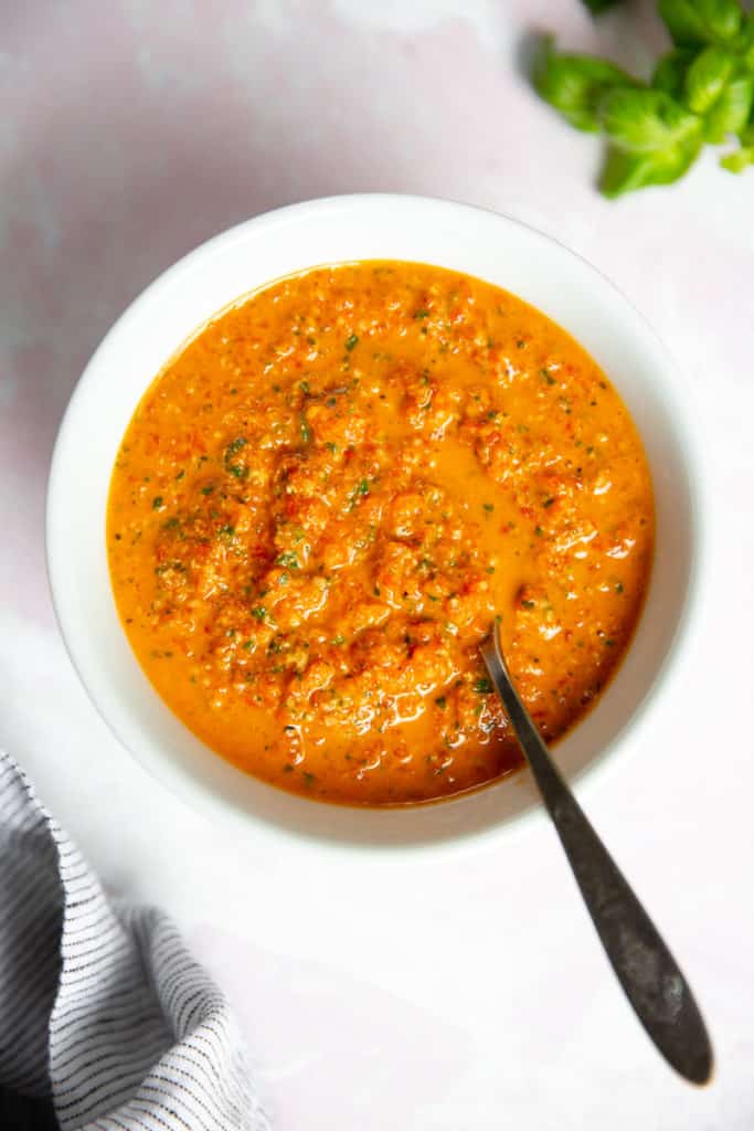Roasted red pepper pesto in a bowl with a spoon. 
