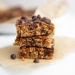 Vegan no bake chocolate chip cookie bars stacked on a piece of parchment paper.