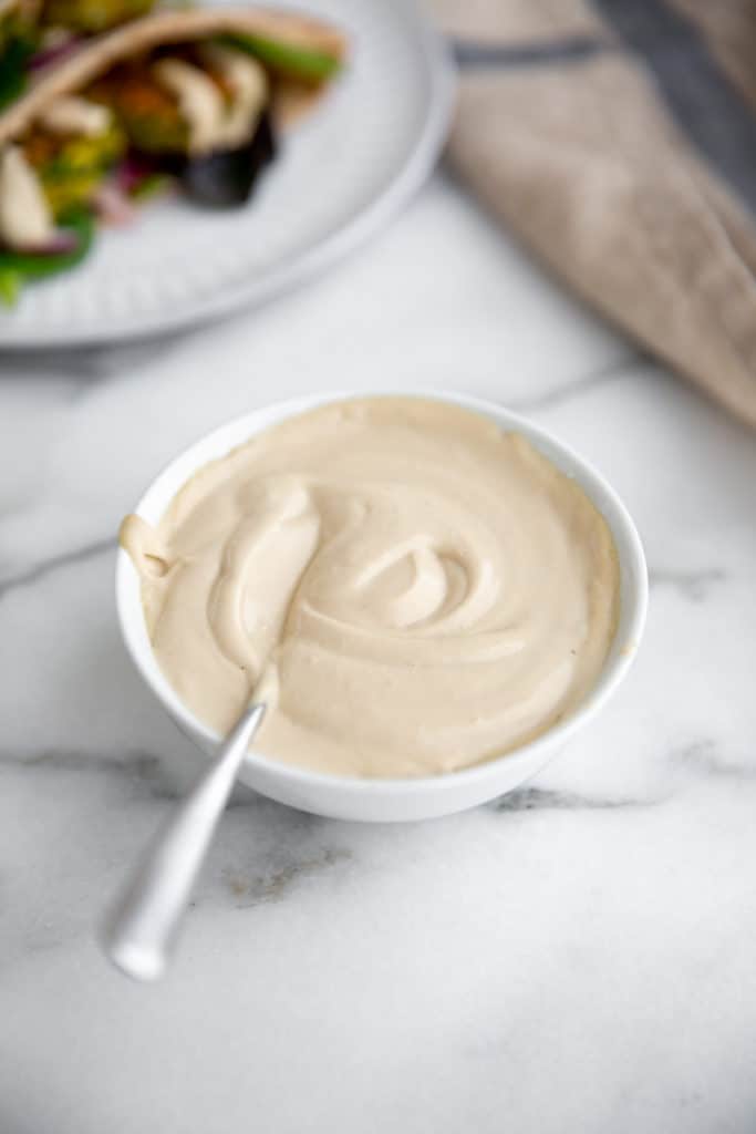 Easy tahini sauce in a bowl with a spoon. 