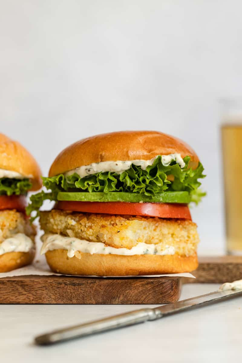 Crispy fried fish sandwich with tomato, avocado, and lettuce on a toasted bun