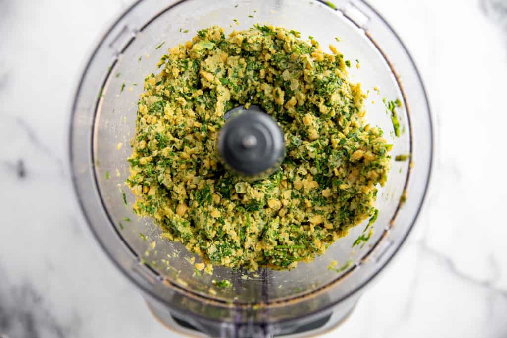 Process shot showing the chickpeas and herbs chopped in a food processor for the healthy falafel recipe. 
