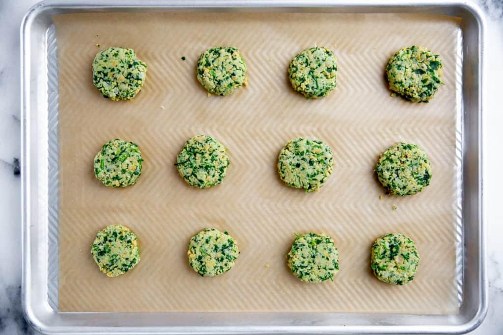 The healthy falafel patties arranged on a parchment lined sheet pan. 