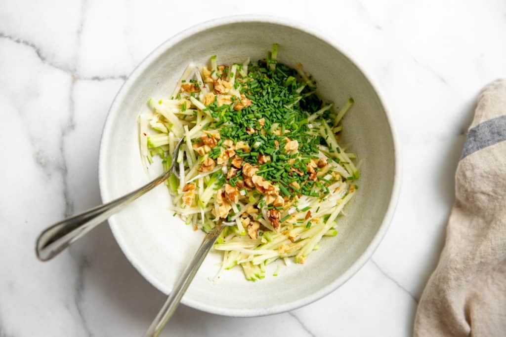 The apple slaw in a bowl with toasted walnuts and chives. 