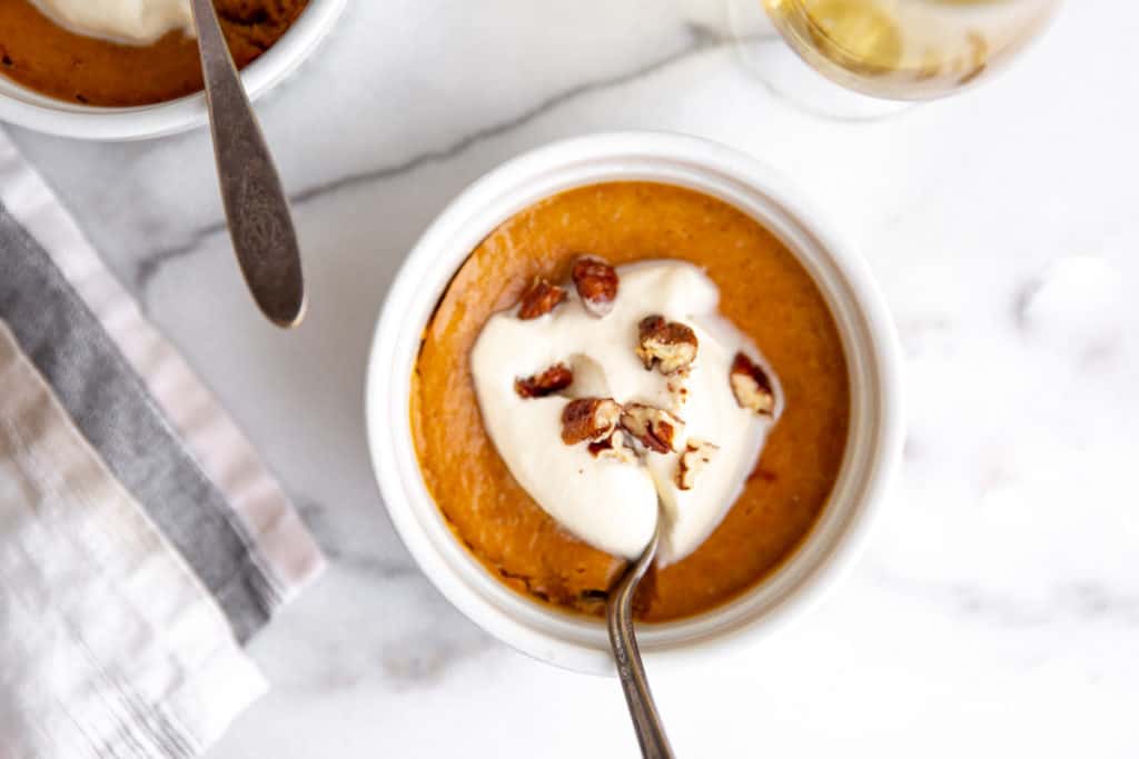 A crustless pumpkin custard topped with whipped cream and chopped maple pecans. 