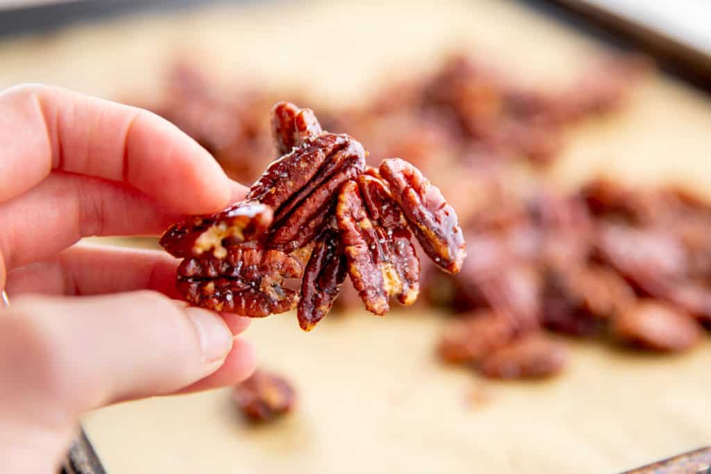 A hand holding a cluster of crunchy maple pecans. 