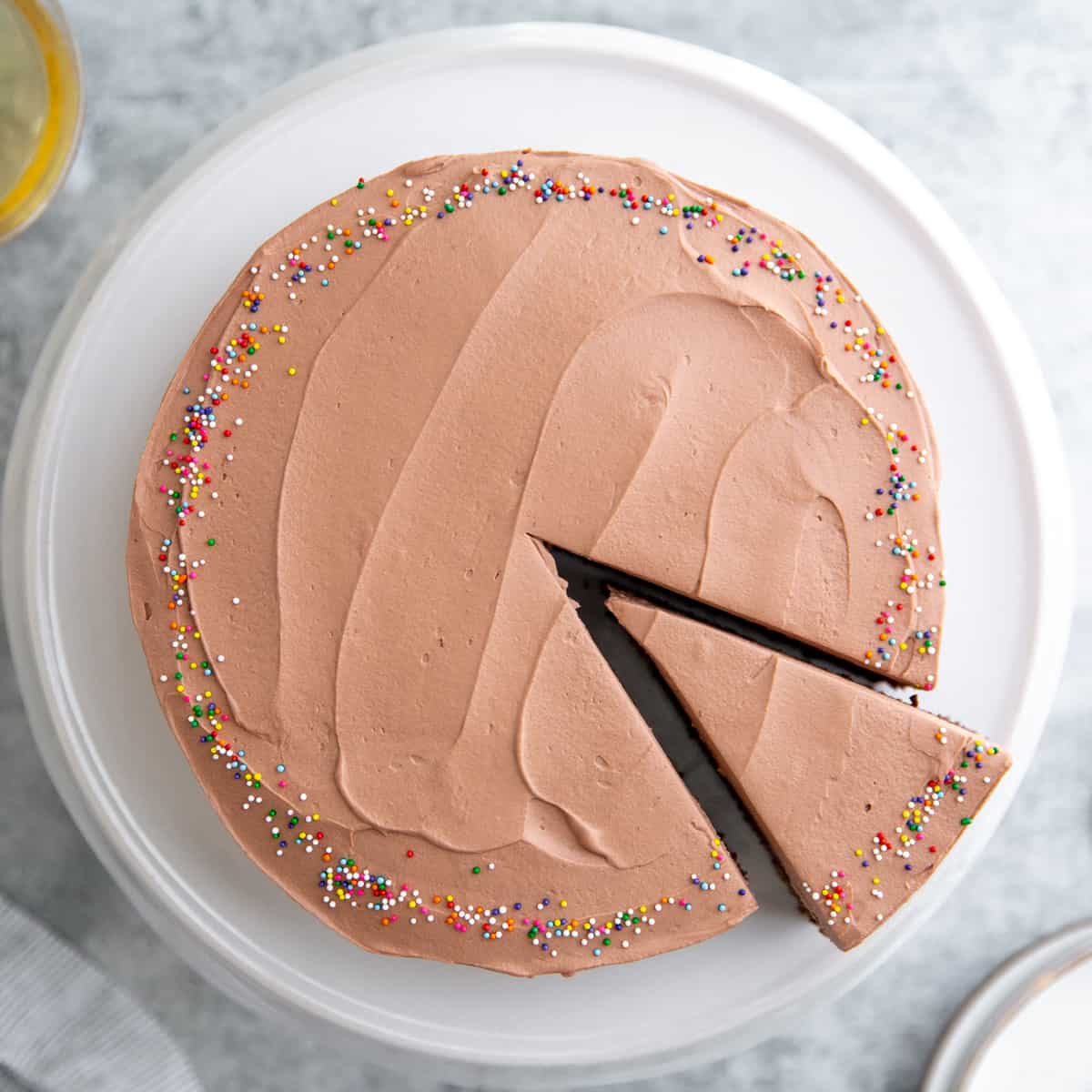 Overhead image of chocolate frosted gluten free cake with one serving sliced.
