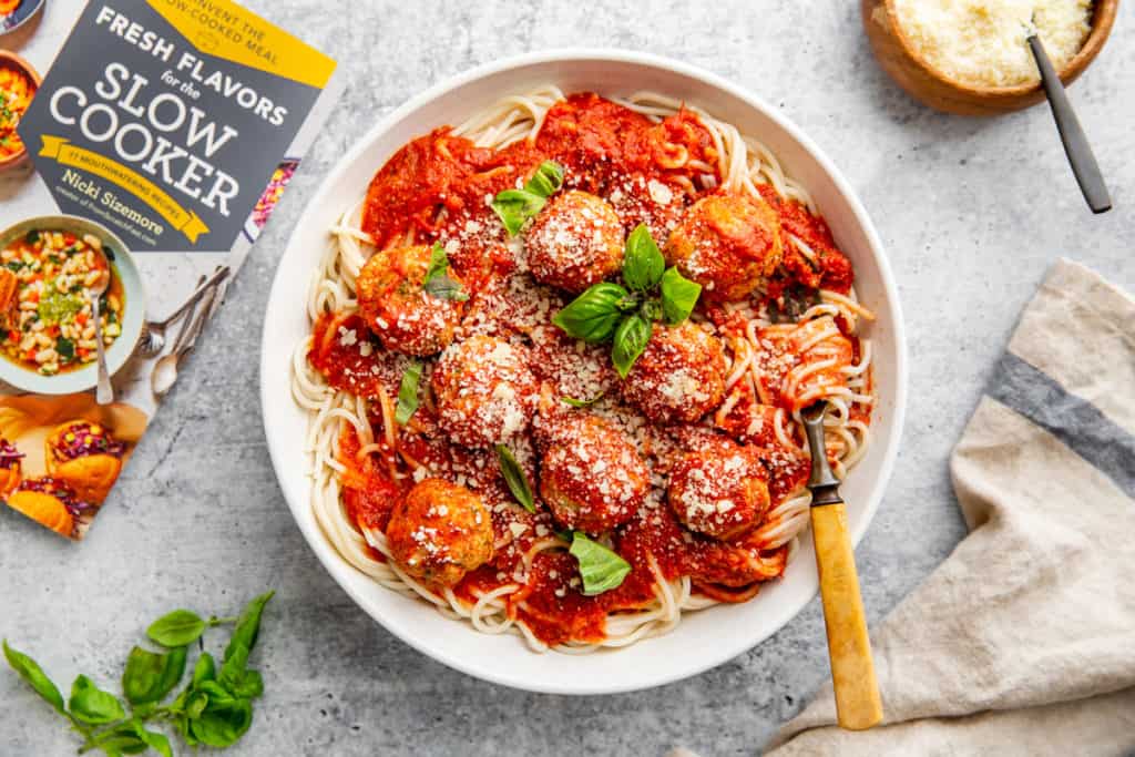 A bowl of meatballs and tomato sauce over spaghetti in a bowl. 