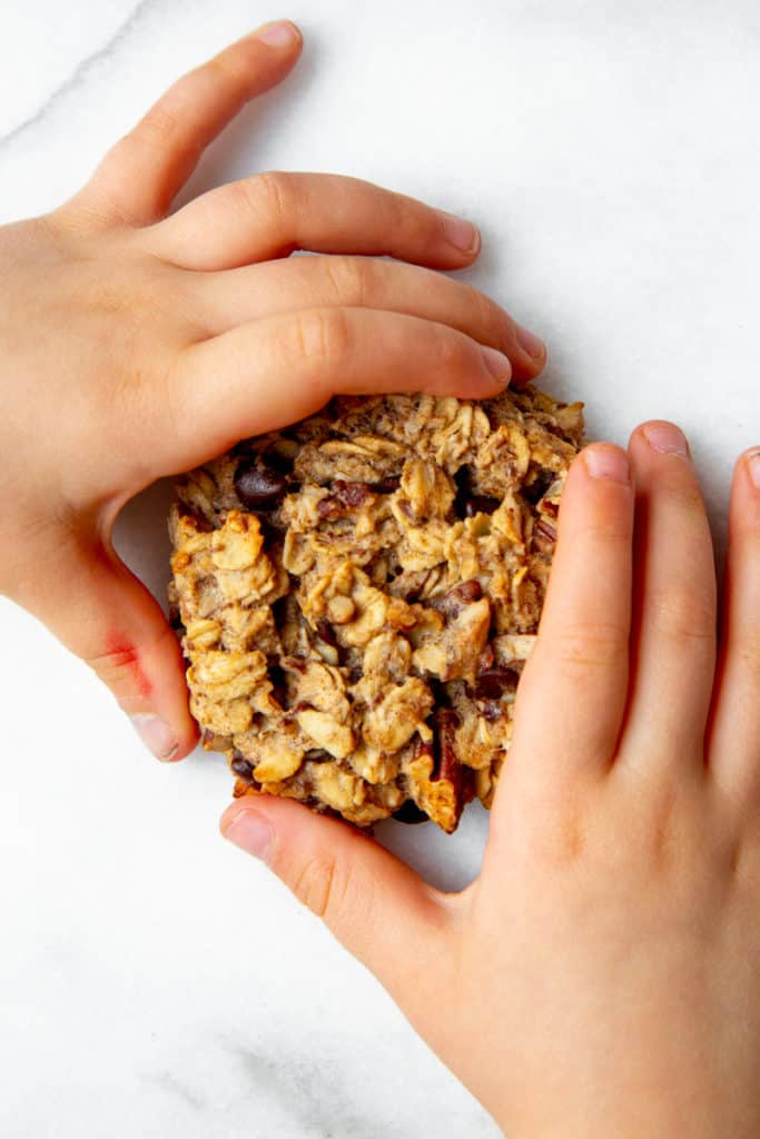 A child's hand holding a banana breakfast cookie.