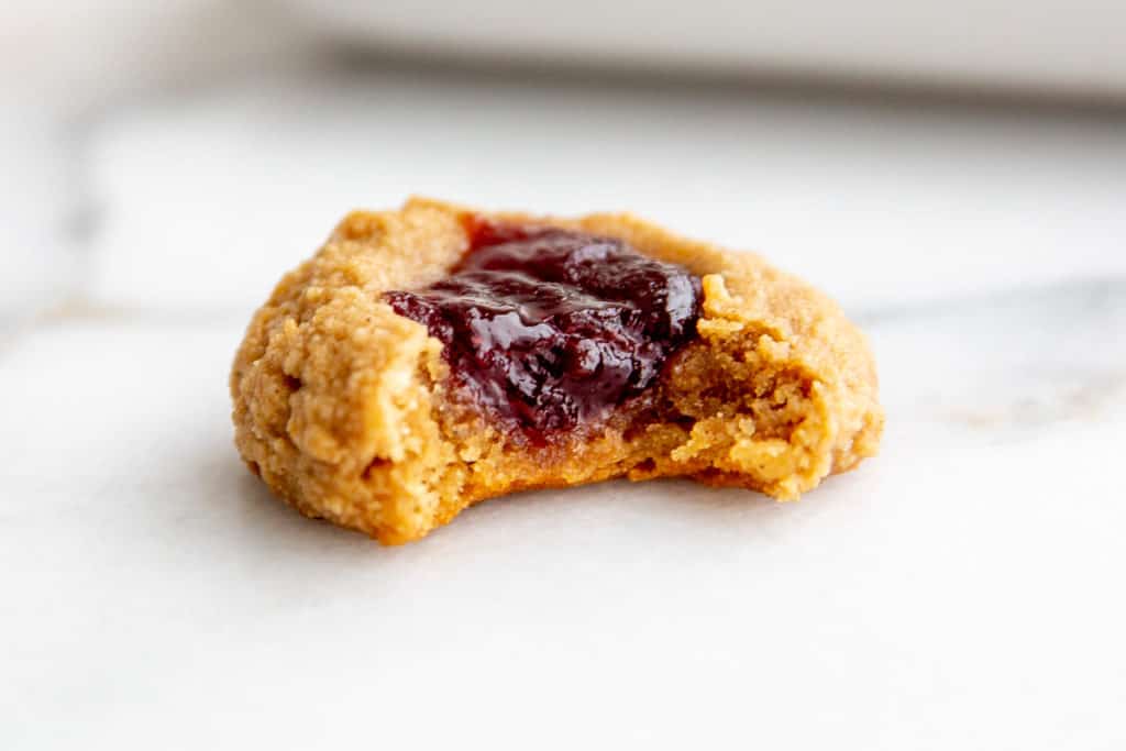 Close up of a gluten free thumbprint cookie with a bite taken out. 