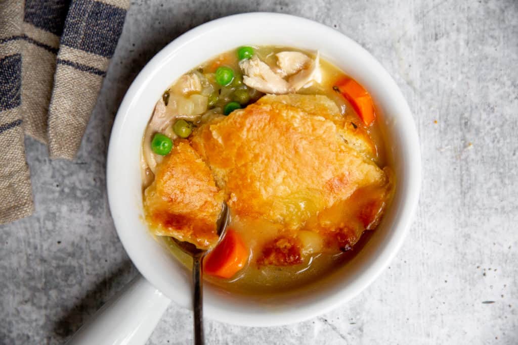 Close up of a serving of gluten free chicken pot pie in a bowl with a spoon. 