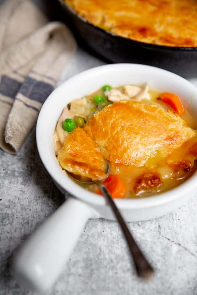 Close up of a serving of chicken pot pie in a bowl with a spoon.