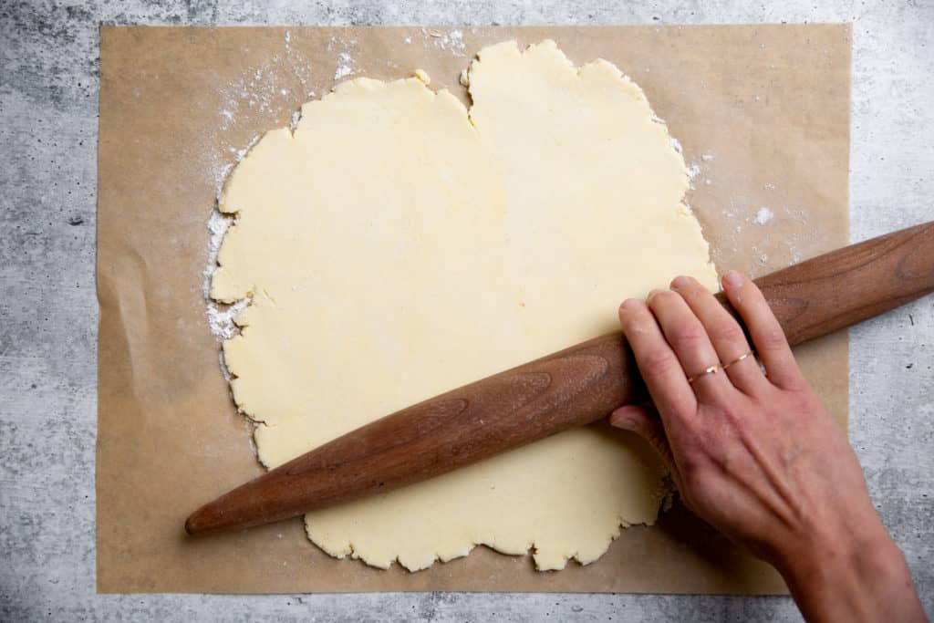 A hand rolling out gluten free pie dough for the pot pie. 