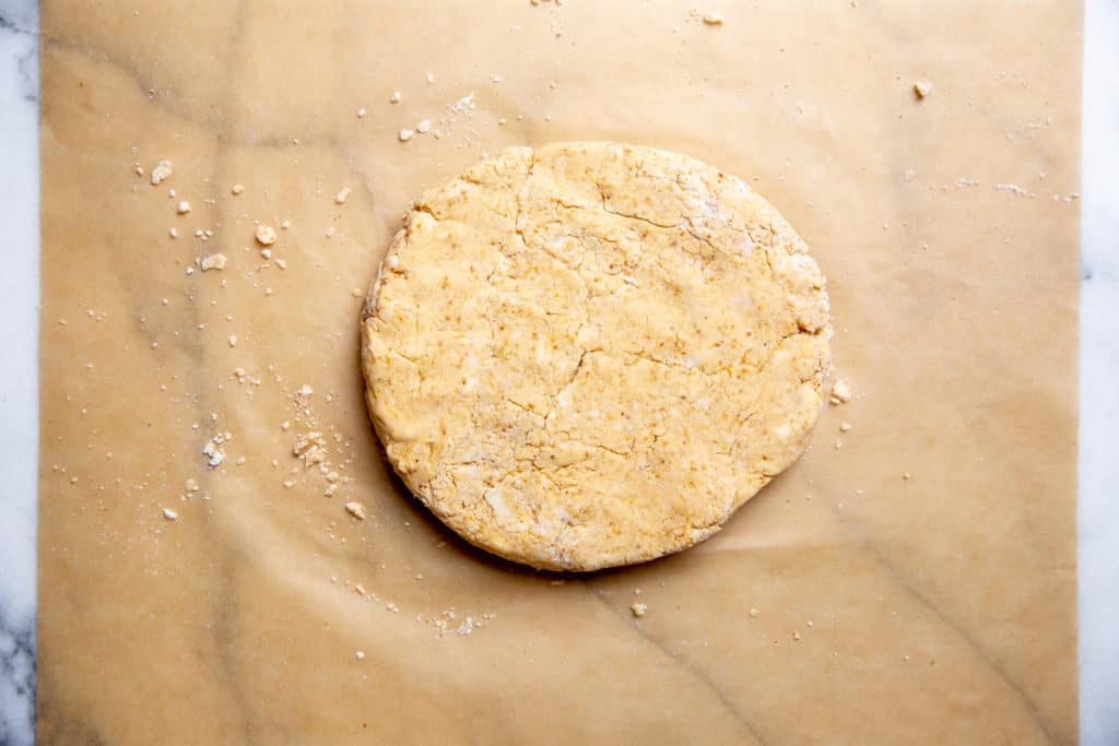 The biscuit dough formed into a round on a piece of parchment paper.