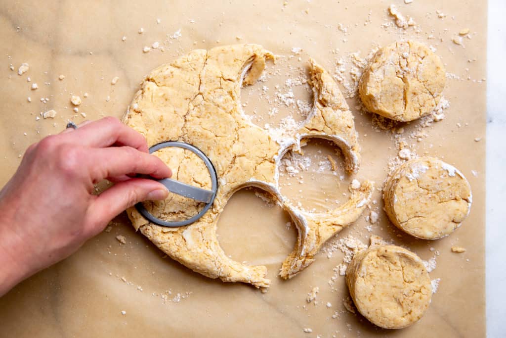 A hand cutting out biscuits using a biscuit cutter.