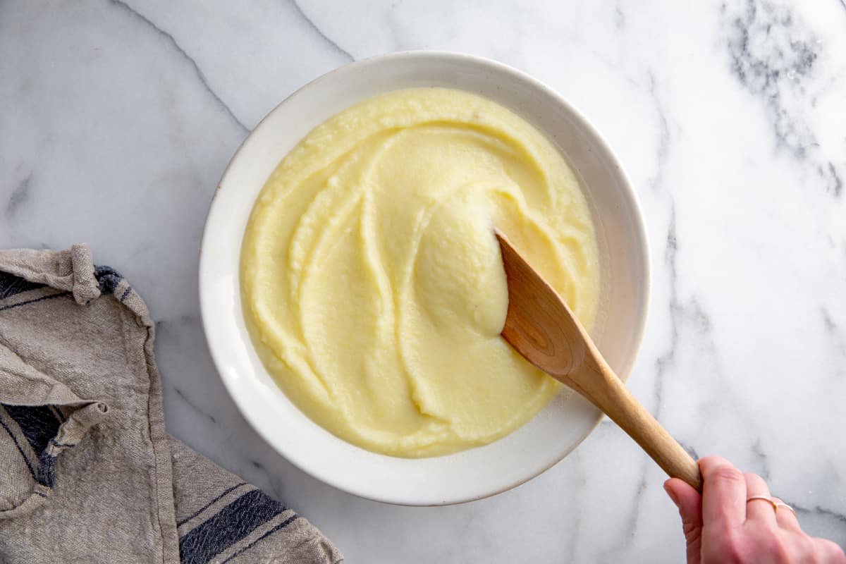 The homemade pomme puree in a serving bowl with a wooden spoon.