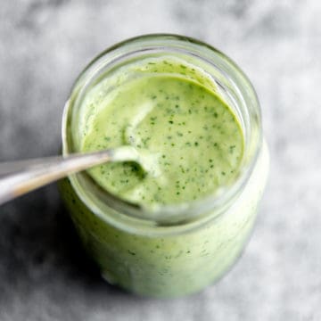 Creamy cilantro lime dressing in a jar with a spoon.