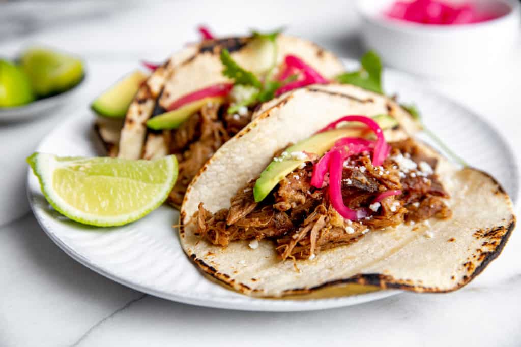 Close up of a slow cooker carnitas taco topped with pickled red onions. 
