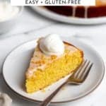 A slice of orange cake on a plate topped with whipped cream.