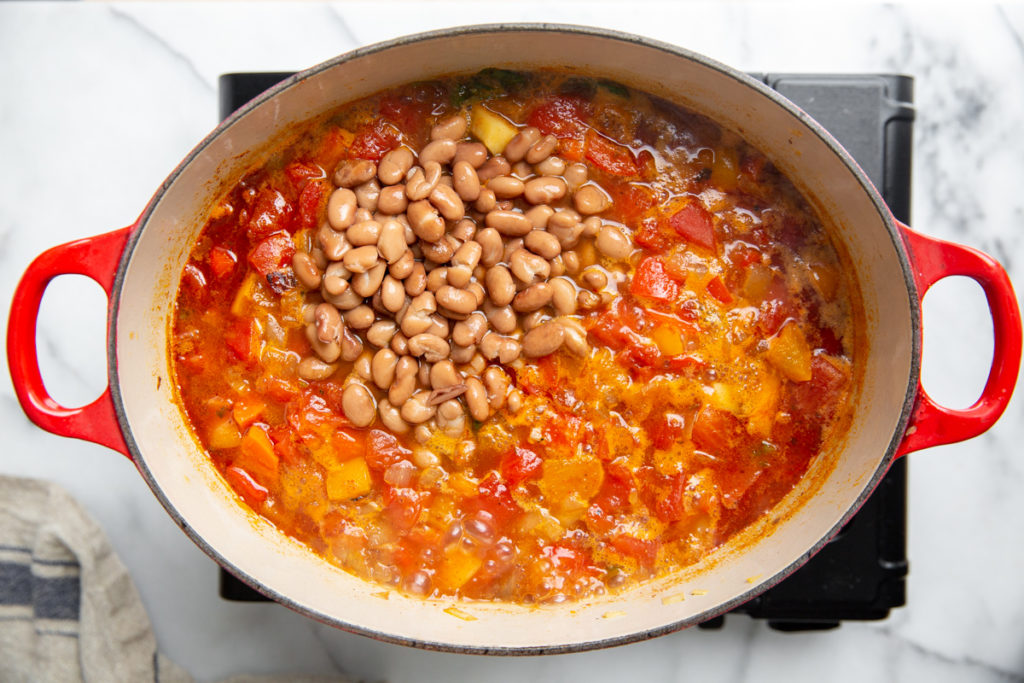 Process shot showing the beans being added to the vegetable chili. 