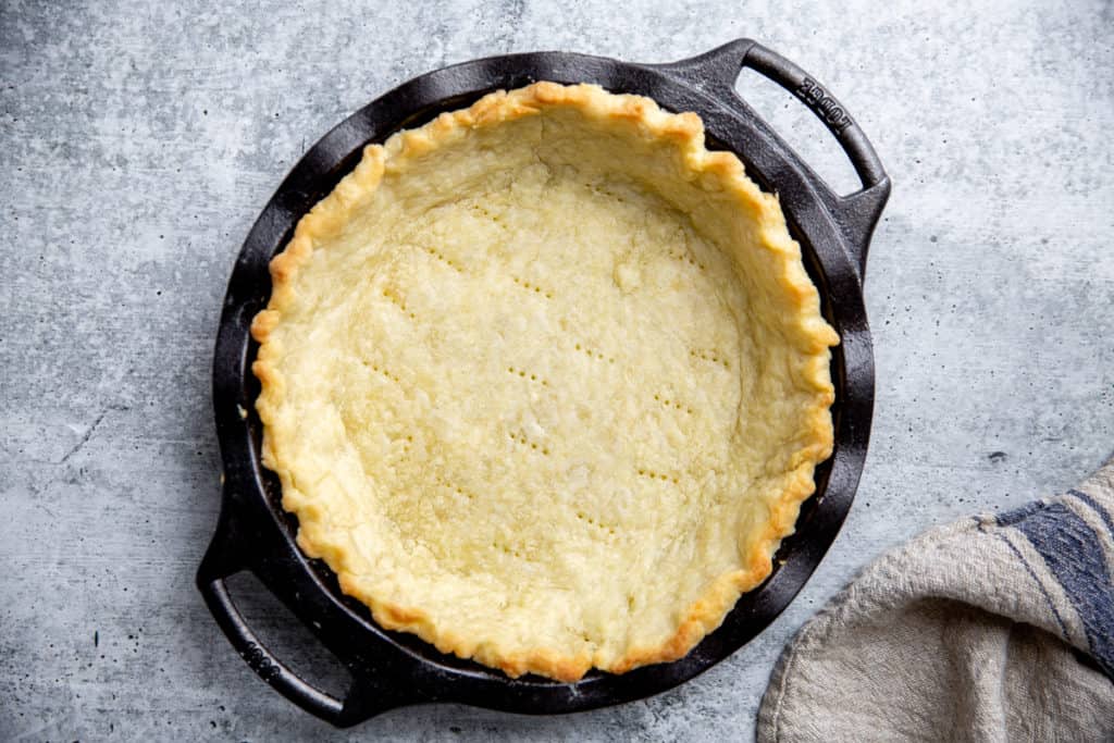 A blind baked pie crust on a gray surface. 
