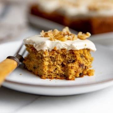A piece of gluten free carrot cake for Easter on a plate with a fork.