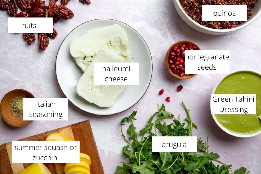All of the ingredients for the halloumi salad recipe on a surface with labels.