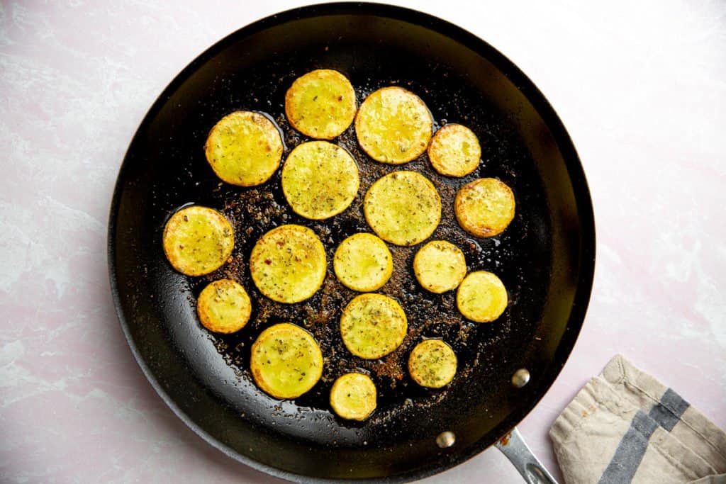 Process shot showing summer squash slices cooking in a large skillet. 