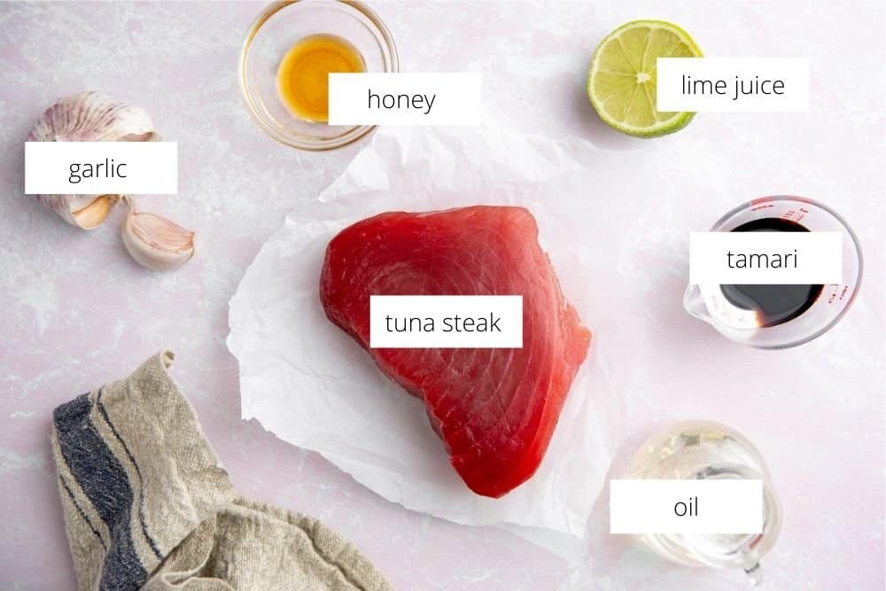 All of the ingredients for the tuna steak recipe on a surface with labels. 