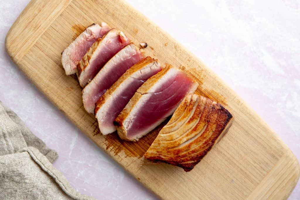 The seared tuna steak sliced on a cutting board.