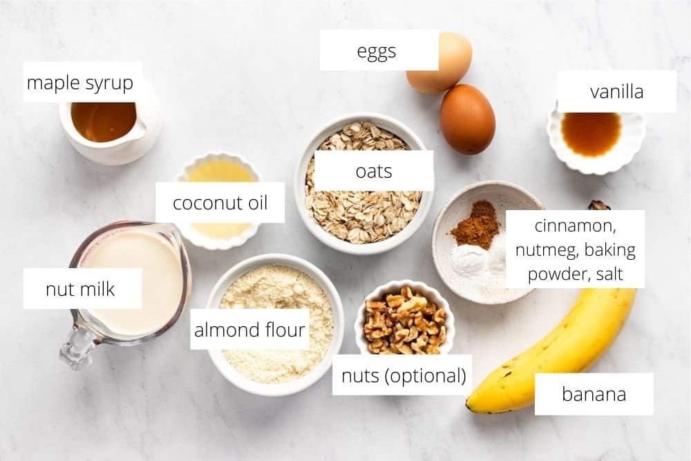 All of the ingredients for the banana oat pancakes recipe arranged on a white surface with labels. 