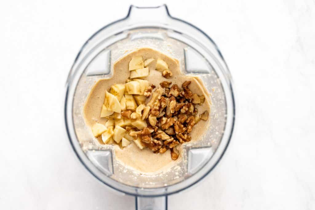 Process shot showing diced banana and nuts going into the banana oatmeal pancake batter.