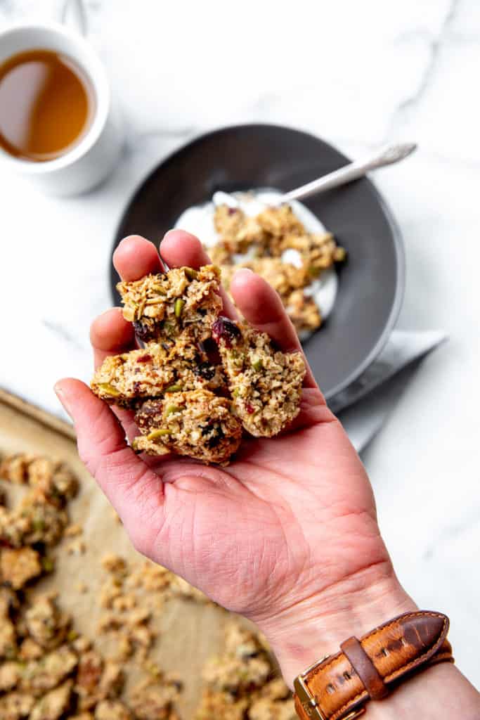 A hand holding granola clusters.